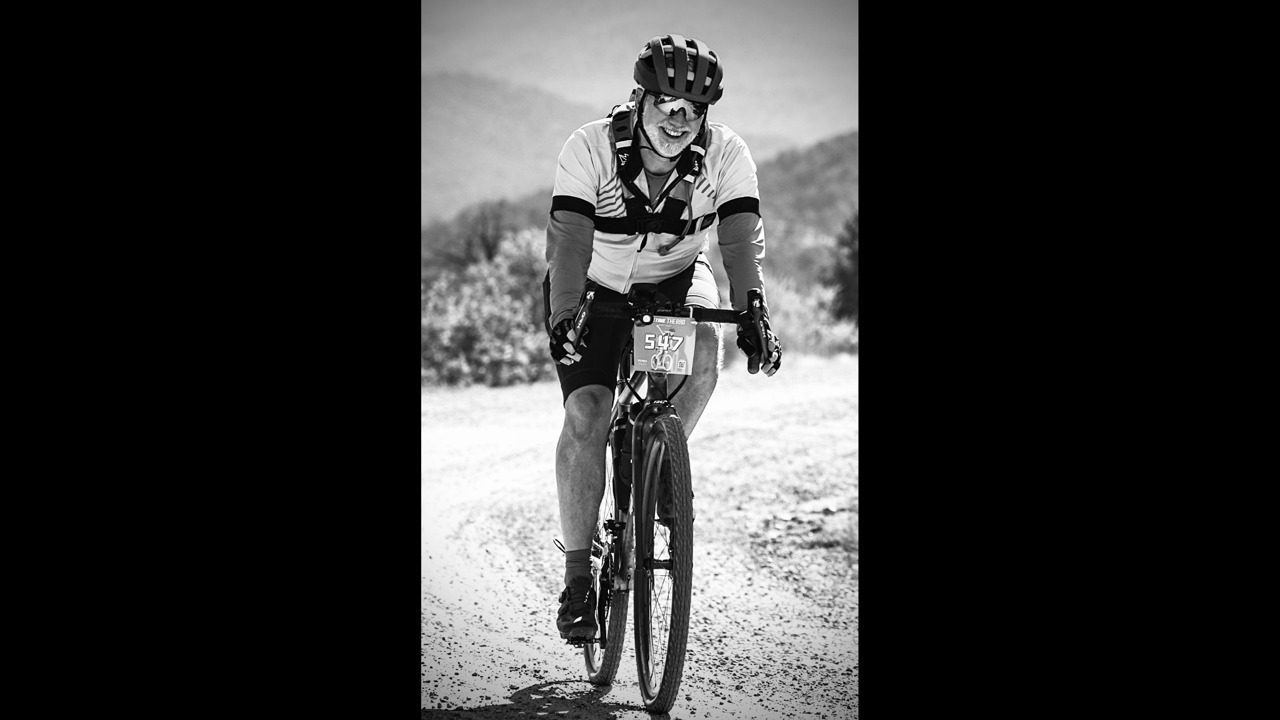 a black-and-white picture of Charles on a bike on gravelly path in Colorado