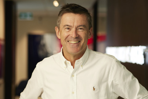 John Wylie standing and smiling with hands on hips