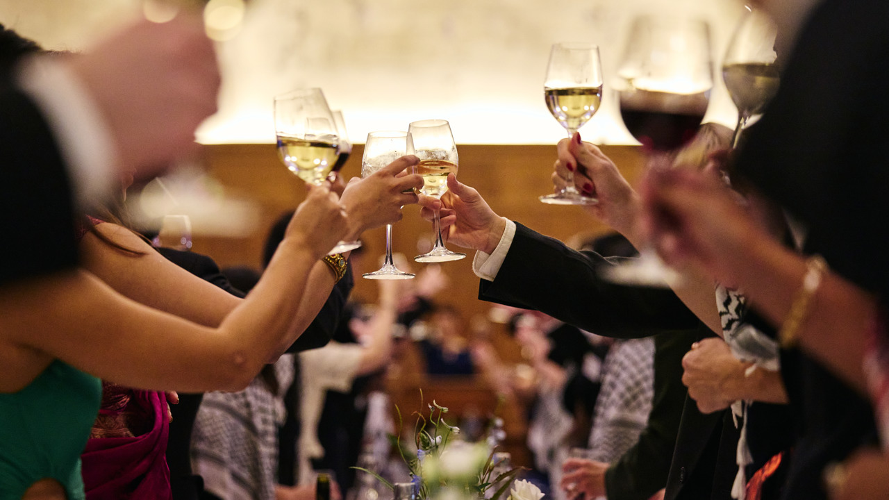 Hands raised with glasses of wine for a toast.