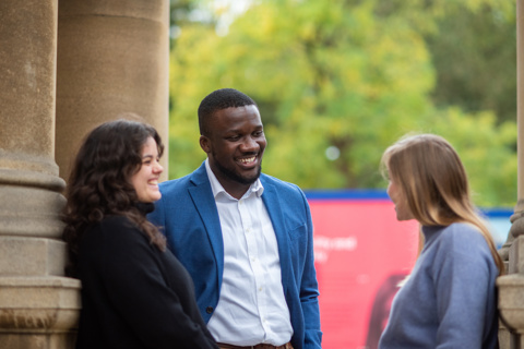 An image of three students standing and talking outside the Rhodes House building