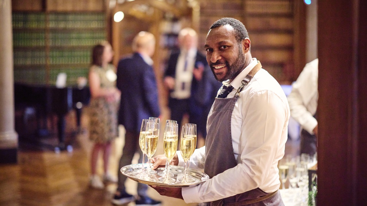 Waiter with tray of sparkling wine welcoming guests into the Reception Room.