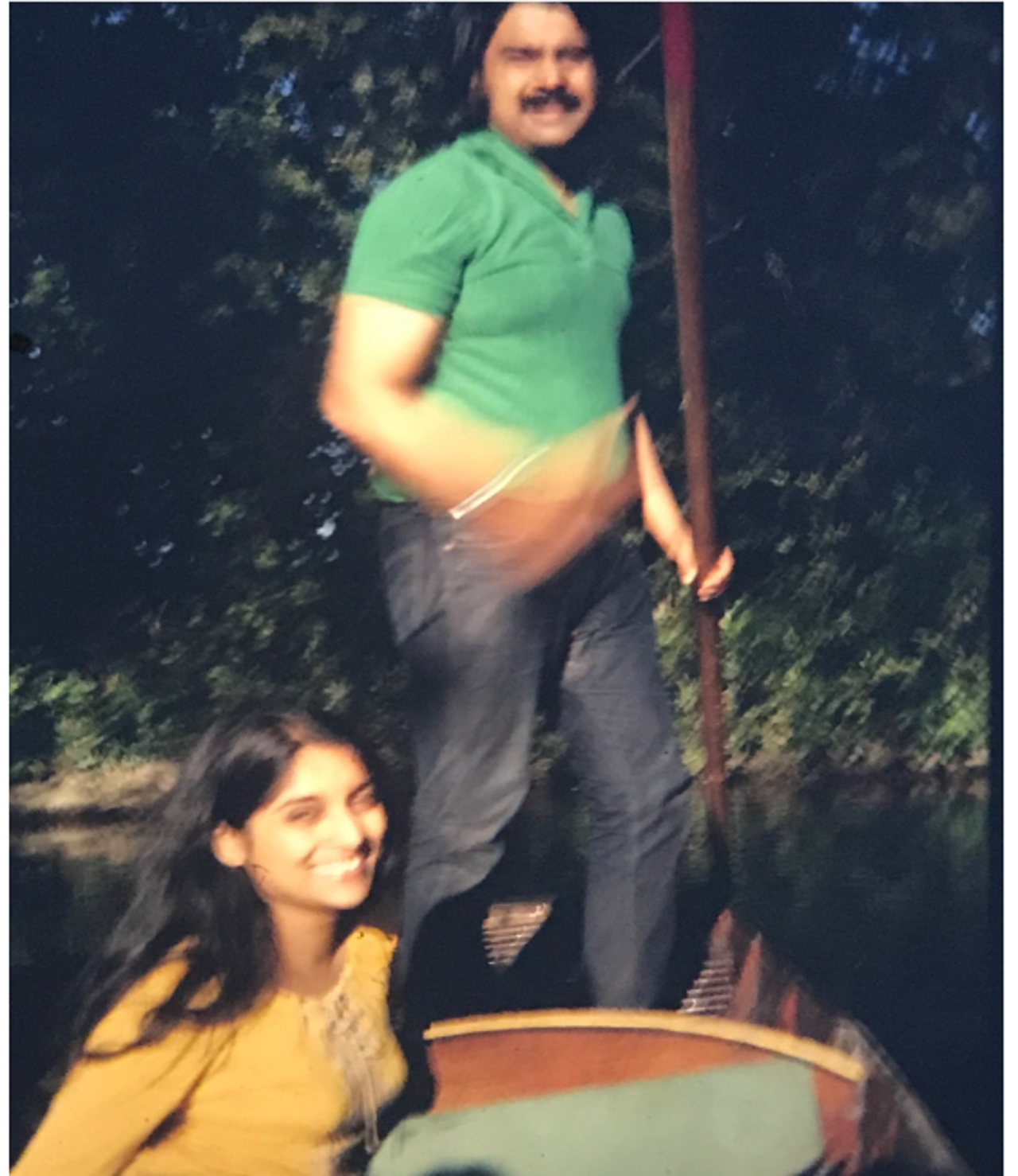 The picture shows Jahar holding a paddle and Sunita sitting on the boat. Sunita is wearing a yellow top and Jahar is in a green t-shirt.