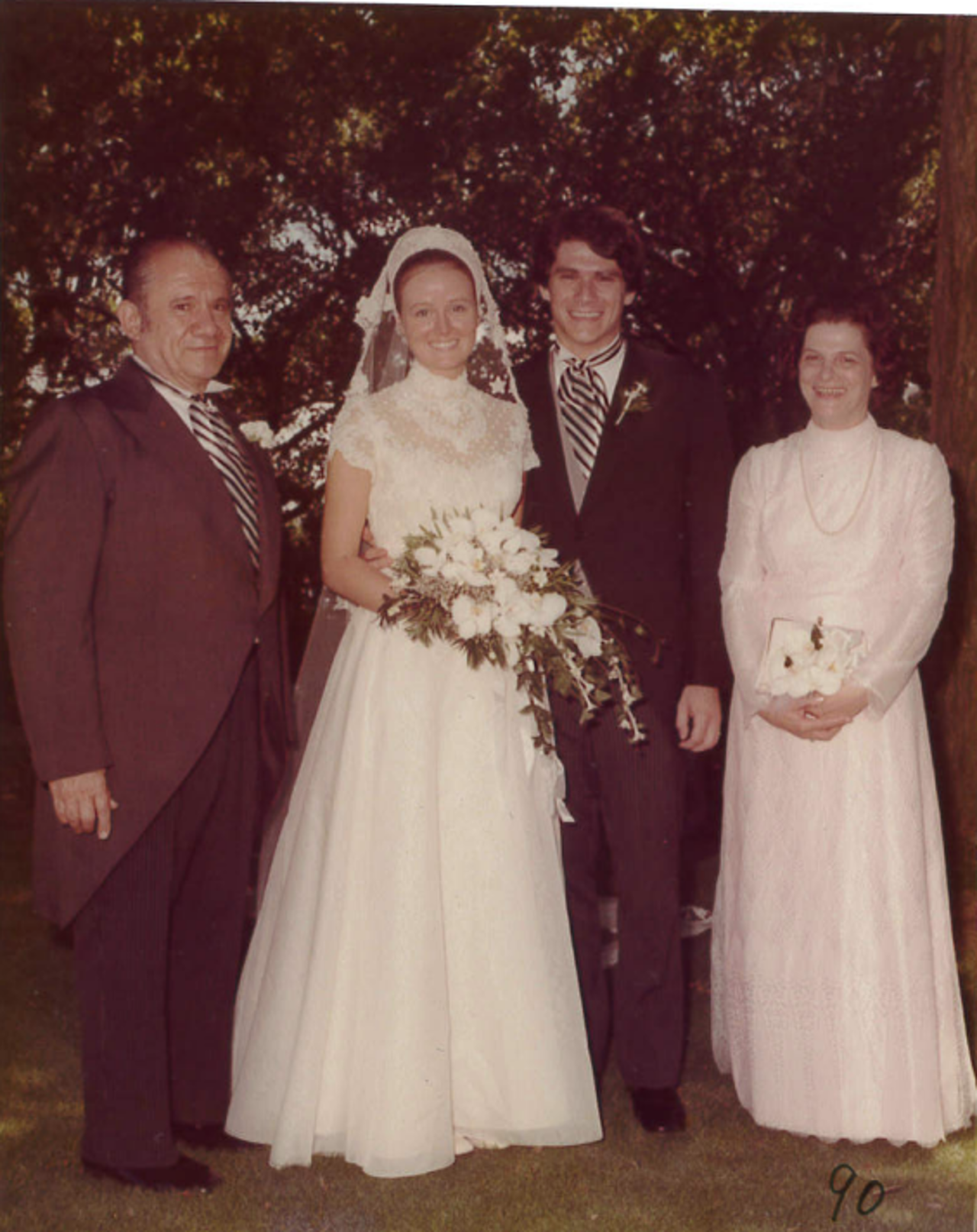 Peter in a suit with Rita to his left in a wedding gown, with two friends smiling alongside them.