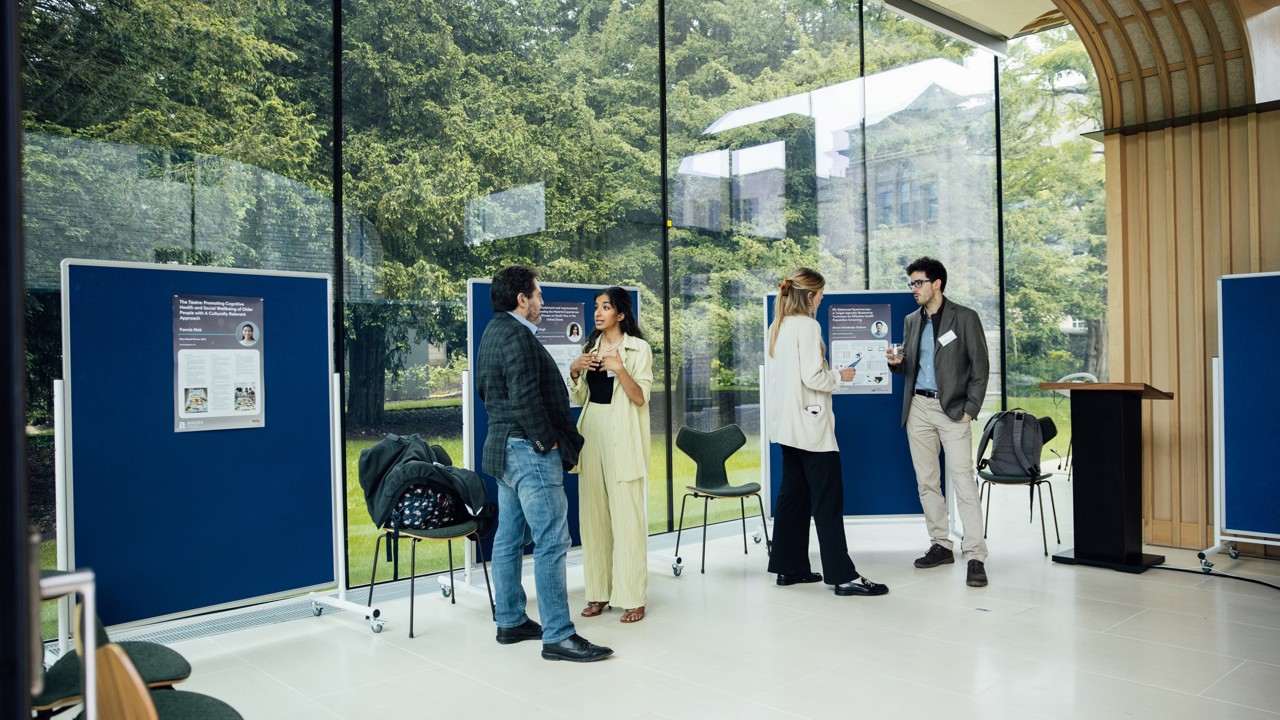 Guests attending an exhibition in the Rhodes House Glass Pavilion with exhibits on display boards.